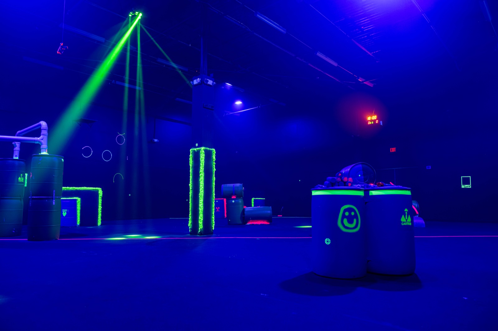 The Blast'D! arena floor under blacklight, with glowing green bunkers and a sweeping light beam