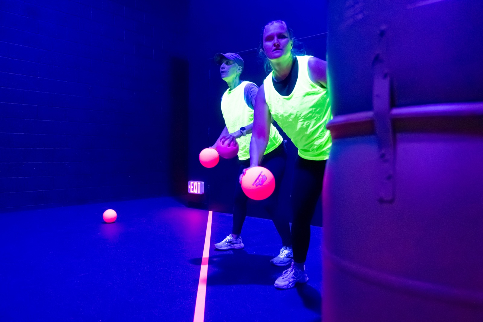 Two players in neon jerseys crouched with glowing pink dodgeballs, ready to throw